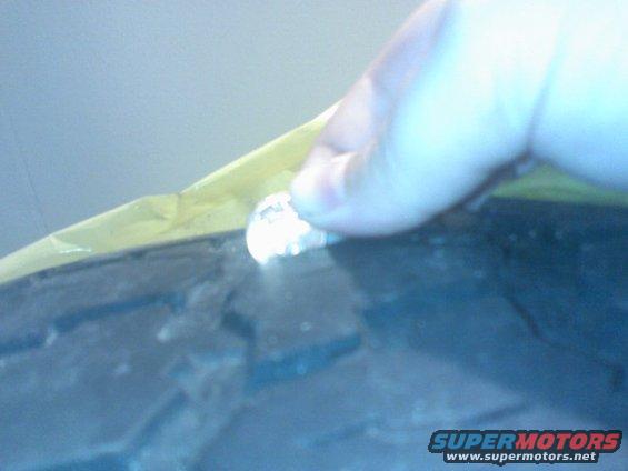 Close-up of a tire with yellow tape and a finger touching a small object