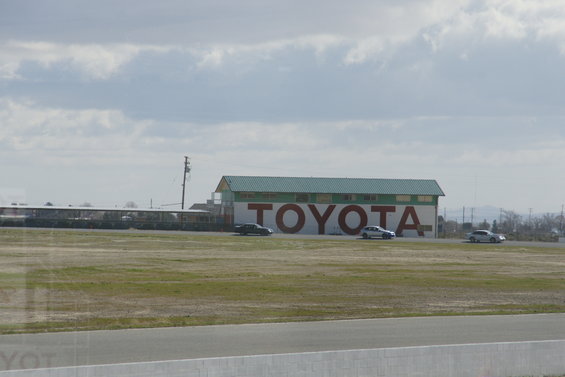 Toyota building with three cars driving on a track in front