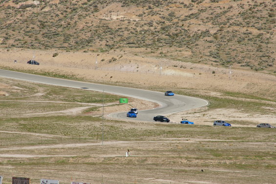 Multiple cars on a winding race track in a desert landscape