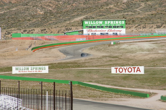 Dark car on a winding race track with Willow Springs and Toyota signs
