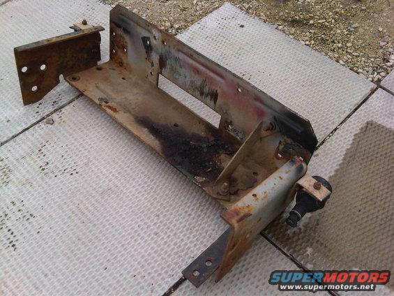 Rusted metal bracket assembly with mounting holes and a small black component