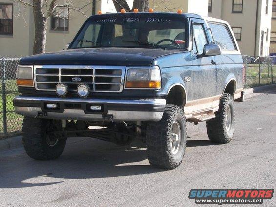 Blue Ford Bronco with lifted suspension and off-road tires, front 3/4 view