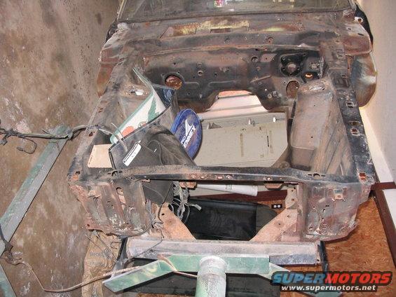 Car frame on stand, front view, rusty