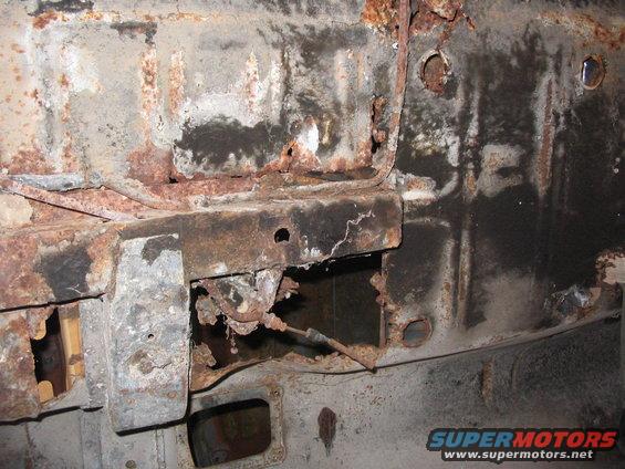 Heavily rusted metal frame with holes and exposed cables, showing significant corrosion