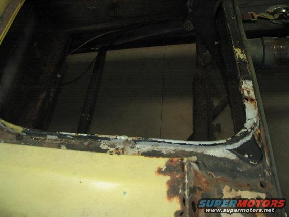 rusted metal frame of a car, showing interior structure and yellow paint