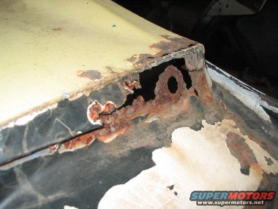 Close-up of a heavily rusted car panel, showing holes and flaking paint