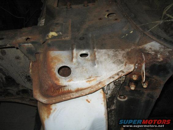 Close-up of rusted car frame with visible bolts and holes