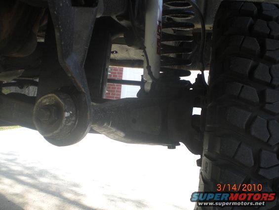 Close-up of vehicle suspension components and a large tire. Date stamp reads 3/14/2010