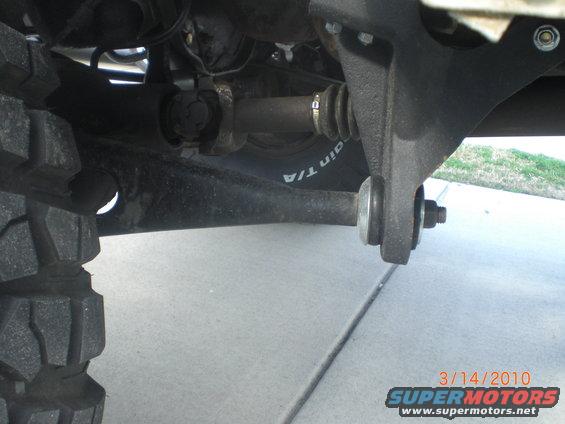 Close-up of a vehicle's suspension, showing the drive shaft and control arm