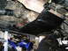 1986 Toyota Hilux - A black skid plate is mounted beneath the transfer case and driveshaft of an off-road vehicle.
