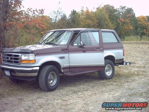 1996 Ford Bronco parked on dirt with trees in background
