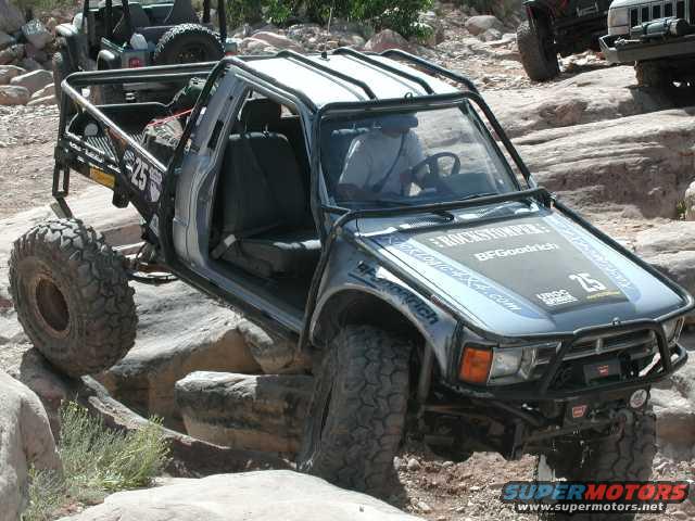 Modified pickup truck with large tires navigating rocky terrain