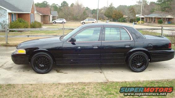black sedan parked in a driveway, aftermarket wheels