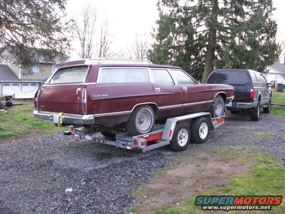 1971 Ford Country Sedan wagon on a trailer, towed by a black SUV