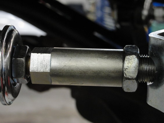Close-up of a metal linkage assembly with hex nuts and threaded rod