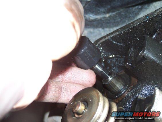 Hand adjusting engine valve with tool. Close-up of engine internals