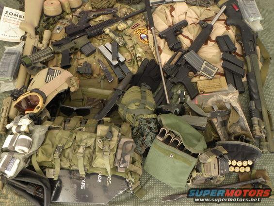 Pile of tactical gear including helmets, body armor, rifles, handguns, shotguns, knives, and ammunition