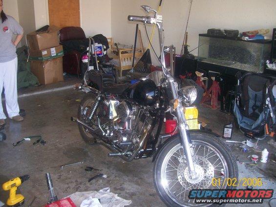 Motorcycle parked in a garage with tools on the floor and boxes in the background. Date stamp reads 01/02/2006