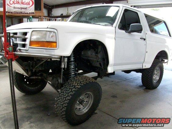 White 1996 Ford Bronco with lifted suspension and off-road tires, jack visible on left