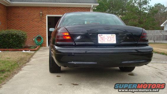 Black 2004 Ford Crown Victoria sedan, rear view, with tinted taillights and a license plate reading ZND-2371