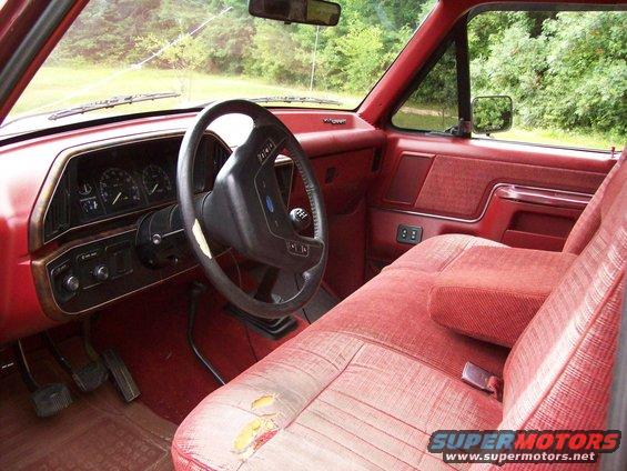Red interior of 1990 Ford F-150 with worn seats and dashboard