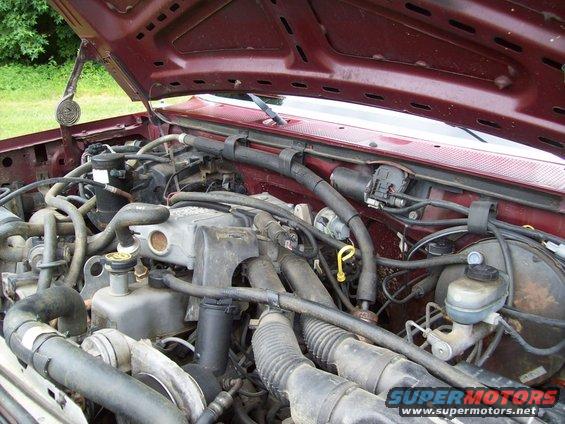Maroon Ford F-150 engine bay with hood open, showing engine components and wiring