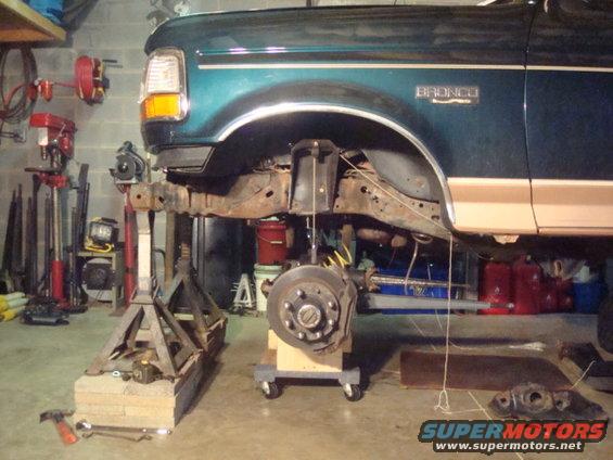 1995 Ford Bronco front end on jack stands, suspension disassembled. Bronco badge visible