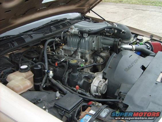 Engine bay of a 1993 Ford Crown Victoria with a supercharger, showing the engine, battery, and coolant reservoirs
