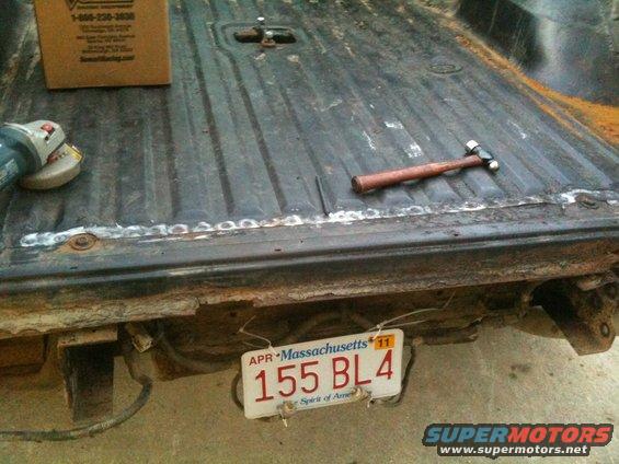 Truck bed with angle grinder, hammer, and Massachusetts license plate