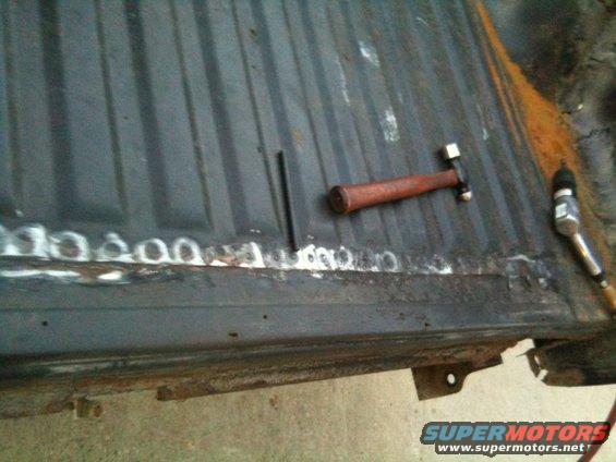 hammer and air tool on rusty truck bed with fresh welds