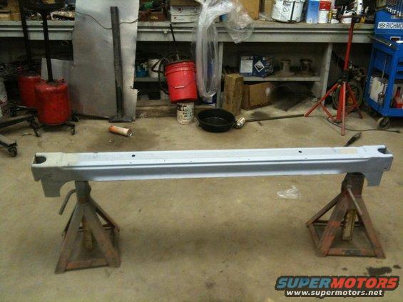 Car rocker panel on two red jack stands in a workshop