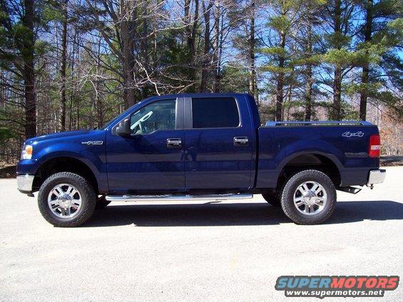 Blue pickup truck parked outside with trees in the background
