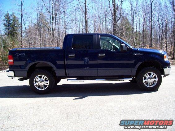 Dark blue four-door Ford F-150 pickup truck, side view, with chrome wheels and running boards