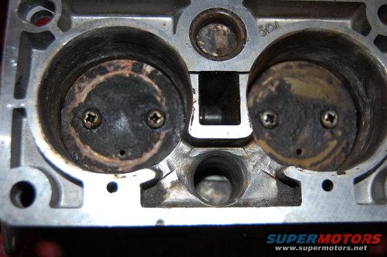 Close-up of two intake ports on an engine cylinder head, showing carbon buildup on the valves