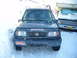 1993 Suzuki Sidekick - A dark blue 1993 Suzuki Sidekick is parked in the snow, a snorkel and various stickers on its front.