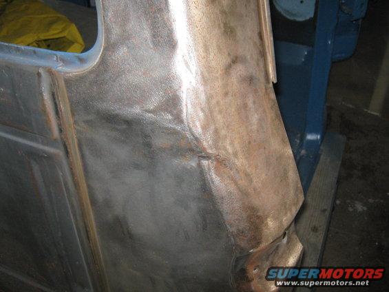Close-up of a dented and rusted truck body panel being worked on