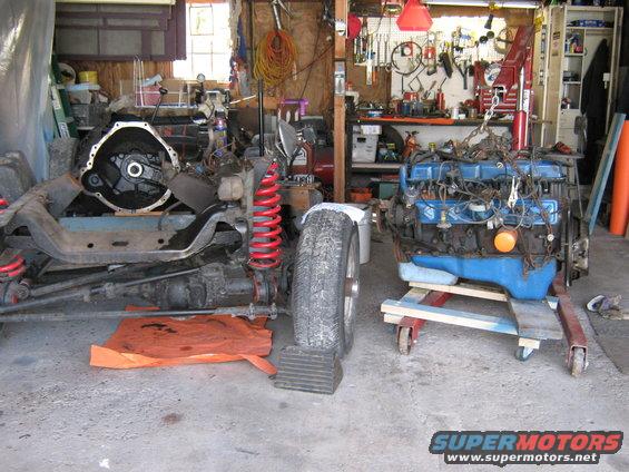 Vehicle chassis with transmission and a separate engine on a stand in a garage