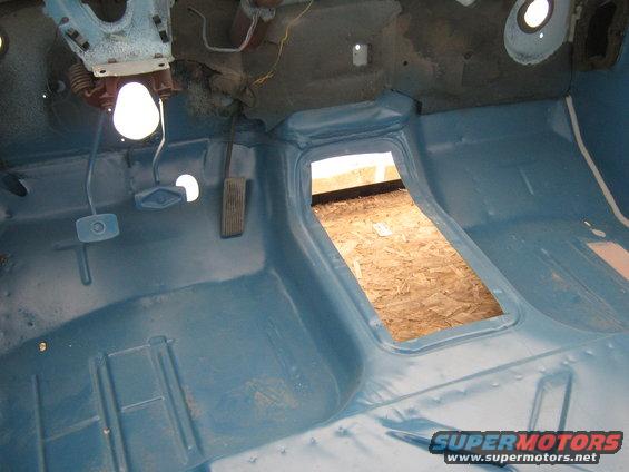 Interior floor and transmission tunnel of a truck, painted blue, with exposed plywood in the tunnel opening