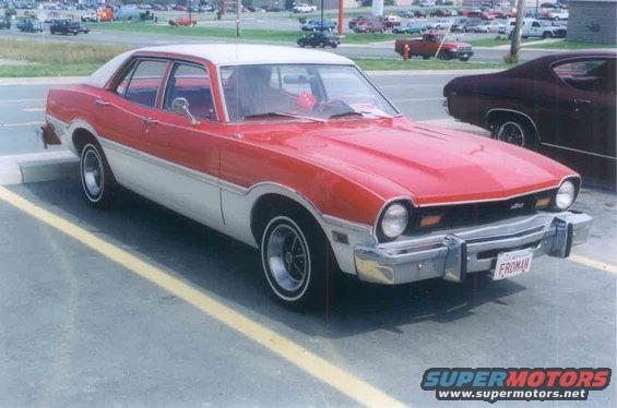 Red and white sedan parked in a lot, front quarter view. License plate reads 'FROMAN'