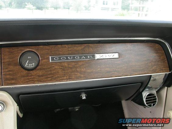 Dashboard of a 1968 Mercury Cougar with wood grain trim, an oil pressure gauge, and "COUGAR" badging
