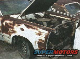Front view of a heavily rusted car with its hood open, showing the engine bay. Watermark reads SUPERMOTORS