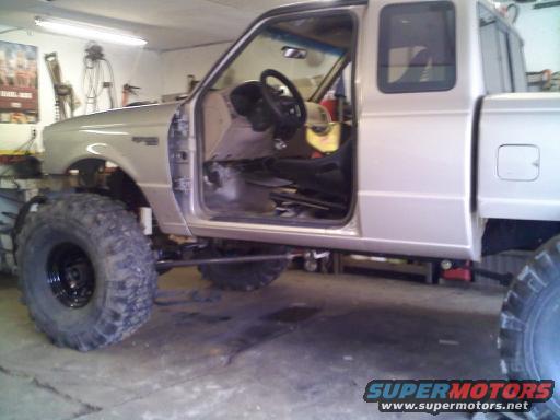 1997 Ford Ranger pickup truck with lifted suspension and large off-road tires, driver's door open