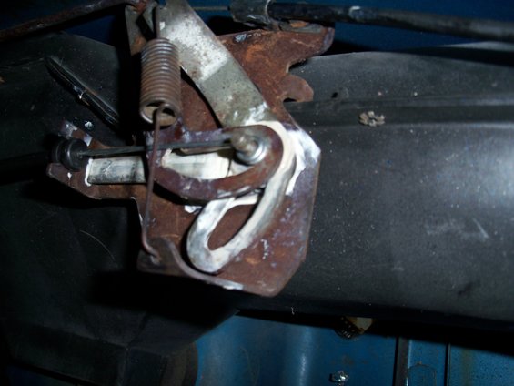 Close-up of a rusty throttle linkage with a spring and cable