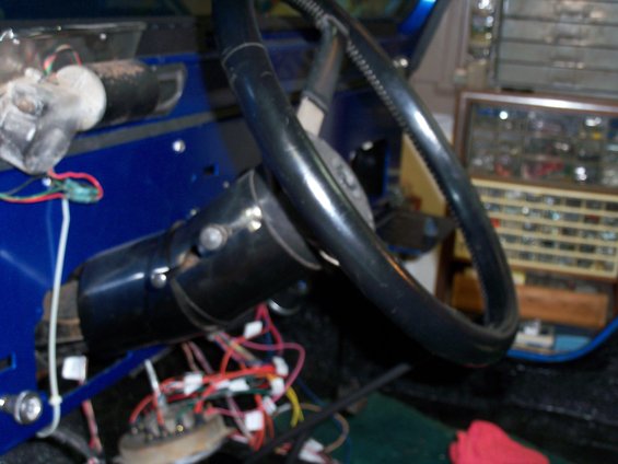 Close-up of a vehicle's interior showing the steering column, wiring, and part of the dashboard