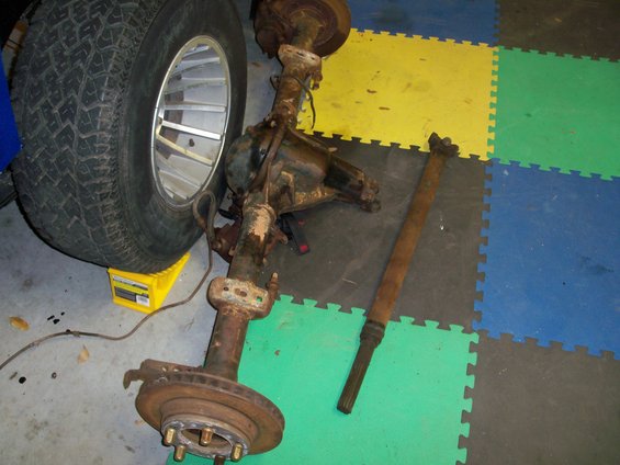 Vehicle axle assembly and a separate driveshaft resting on a tiled floor