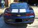 2010 Chevrolet Camaro - Rear view of a blue 2010 Chevrolet Camaro with dual white racing stripes and a man standing nearby.