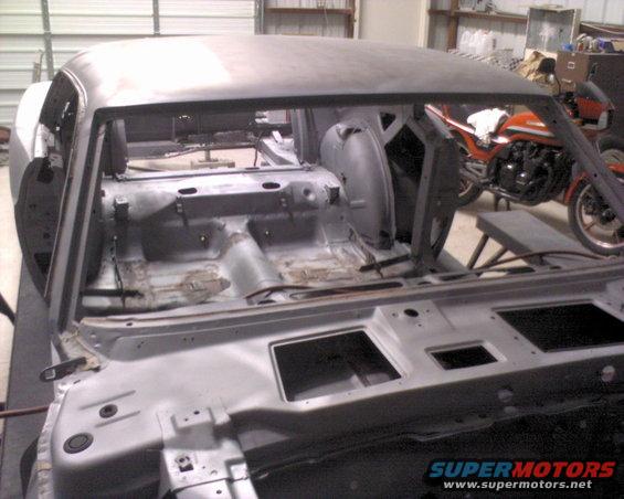 1970 Ford Mustang body shell, stripped down for restoration. Motorcycle visible in background