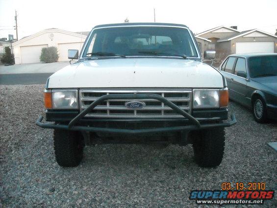 Front view of a white 1988 Ford Bronco with a brush guard and aftermarket wheels