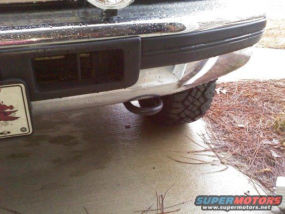 Rear bumper of a truck showing a tow hook and tire tread. License plate visible