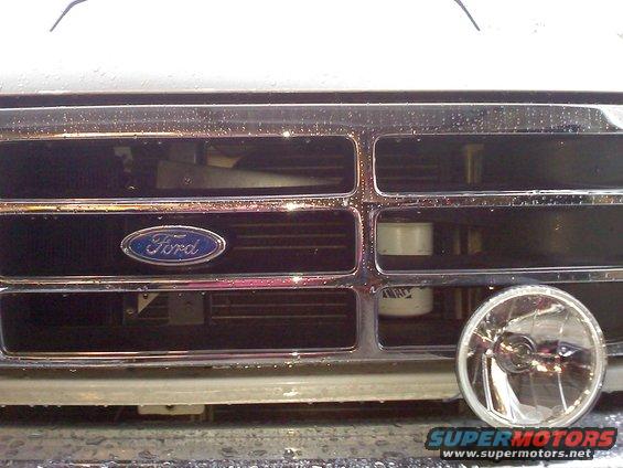 Chrome grille with Ford emblem, a round headlight, and water droplets